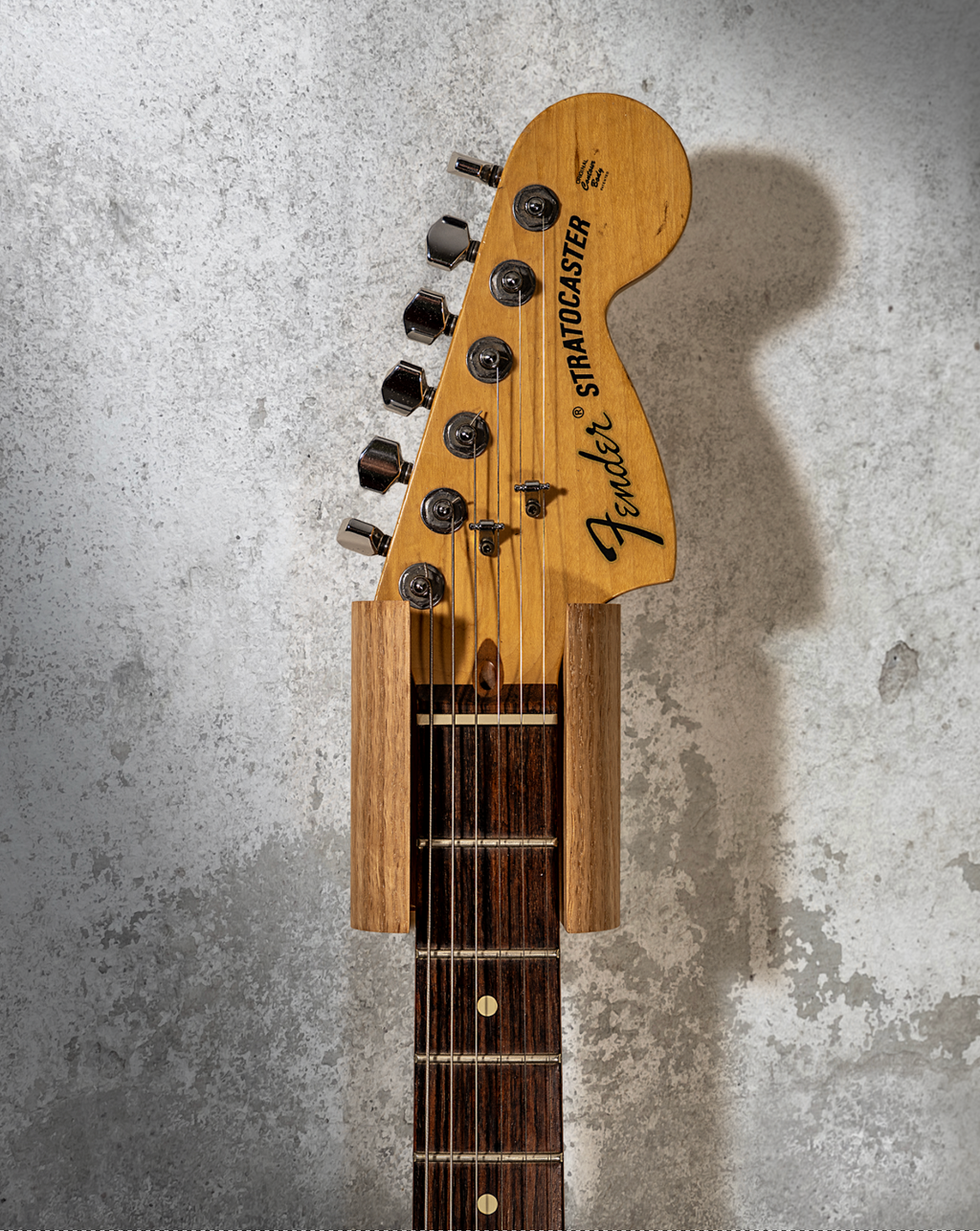 Hanger de madera para guitarra instalado en pared con guitarra eléctrica
