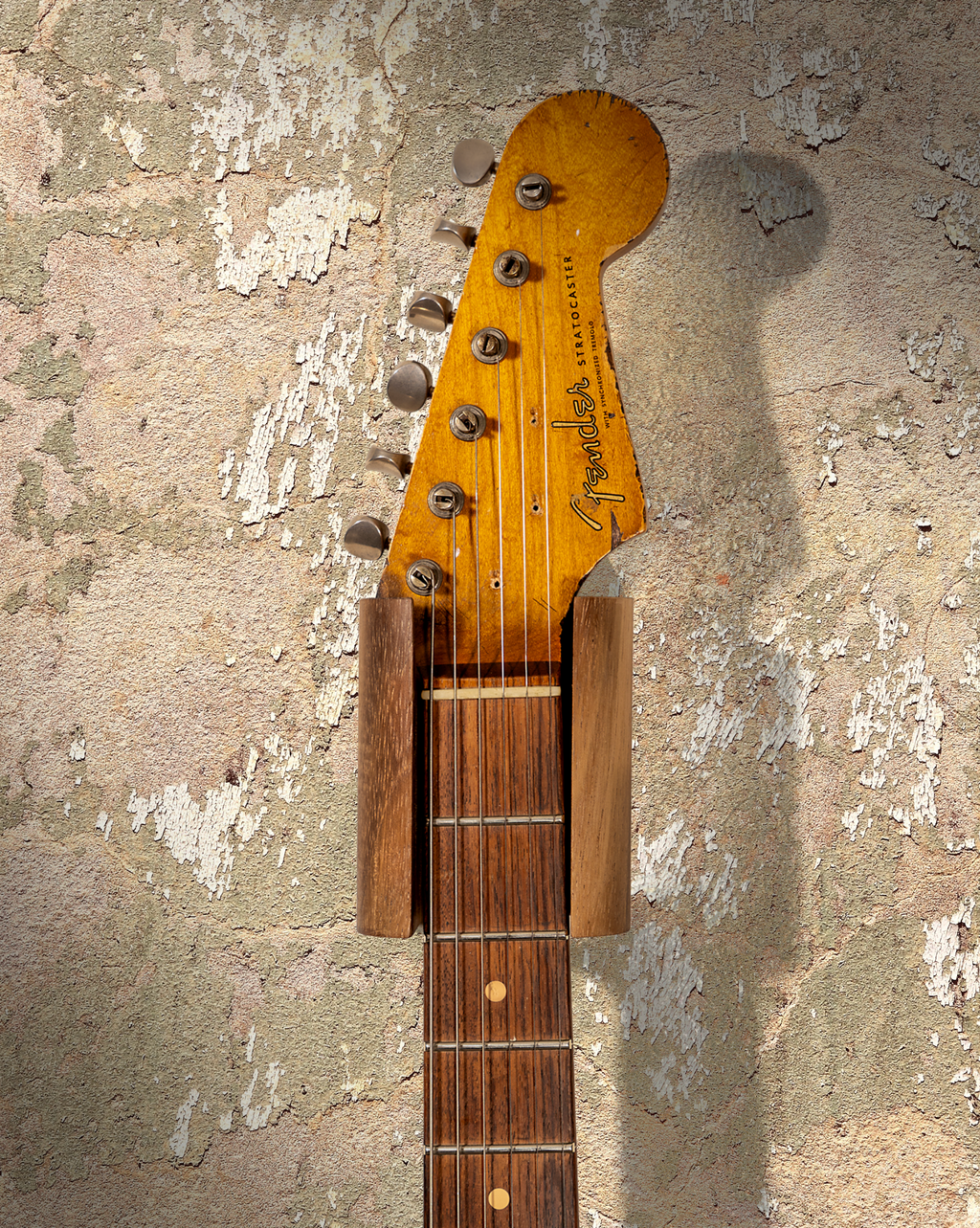 Hanger de madera para guitarra instalado en pared con guitarra eléctrica
