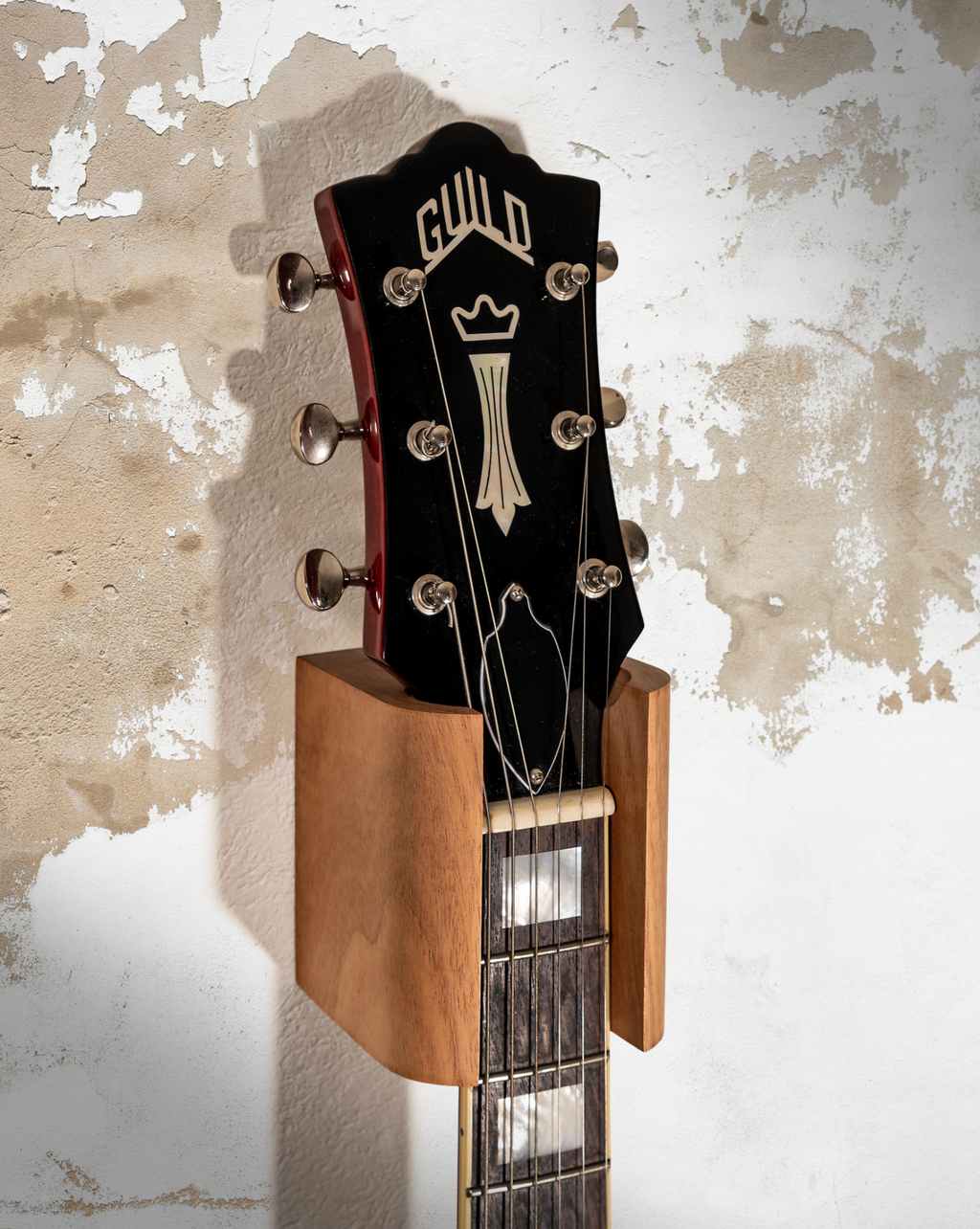 Hanger de madera para guitarra instalado en pared con guitarra eléctrica
